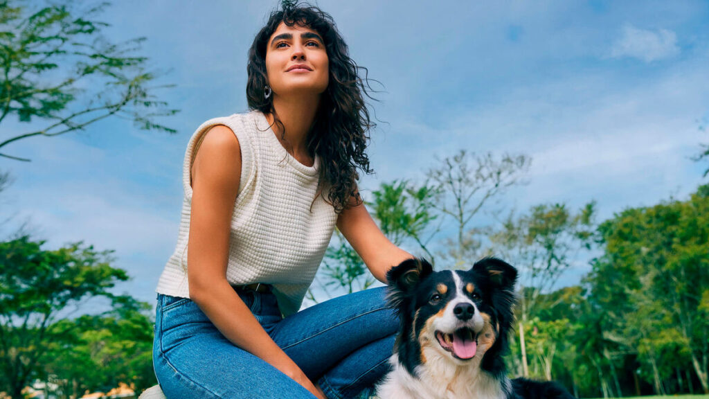 Mulher sorrindo ao lado de um cachorro em parque