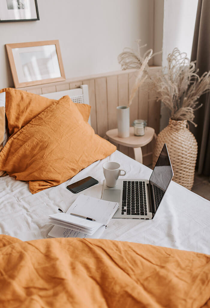 cama com computador e travesseiro laranja