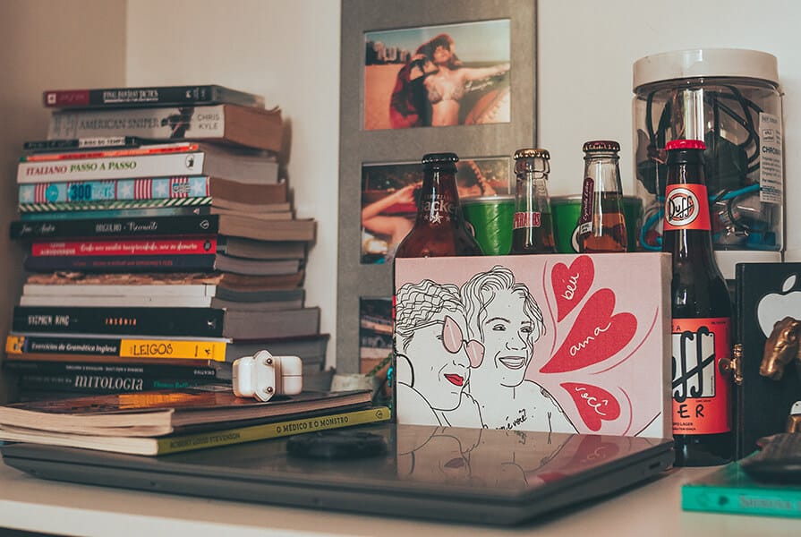 Decoração com livros dispostos na horizontal, fotos e garrafas de cervejas especiais decoração afetiva