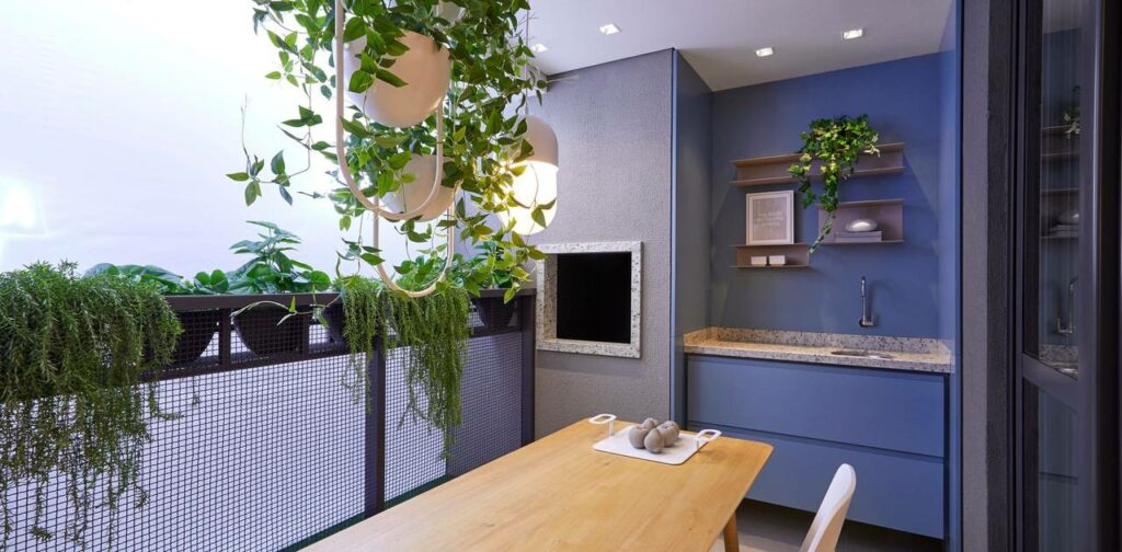 Imagem de área externa de apartamento decorada com plantas, parede azul e mesa em madeira.