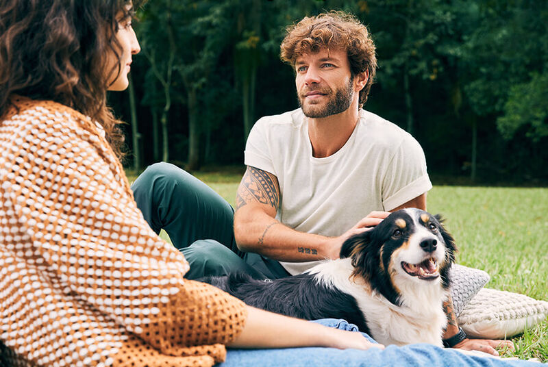 Casal conversando com cachorro em um parque.