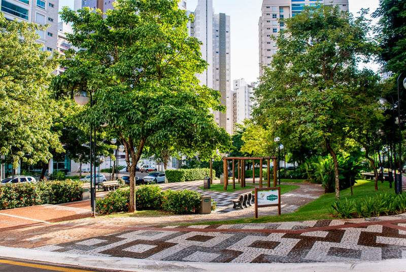 Praça arborizada em área urbana moderna.