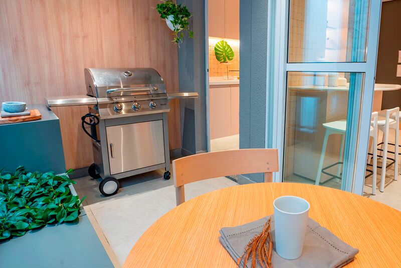 Churrasqueira em varanda moderna com mesa e plantas.