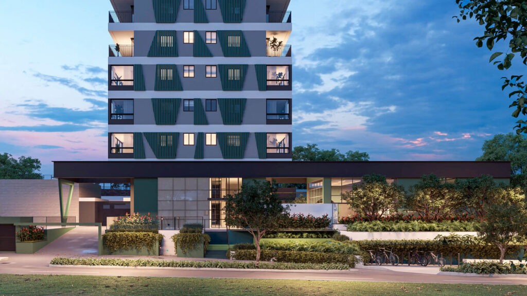 Edifício moderno com áreas verdes e janelas iluminadas.