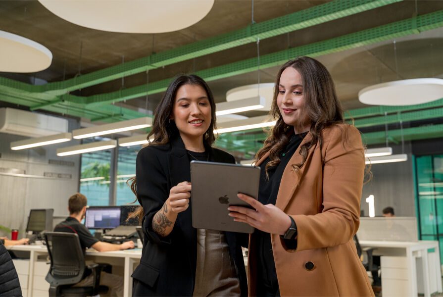 Duas mulheres analisando dados em um tablet no escritório