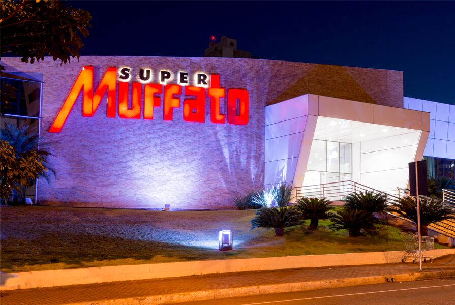 Fachada iluminada do Super Muffato à noite