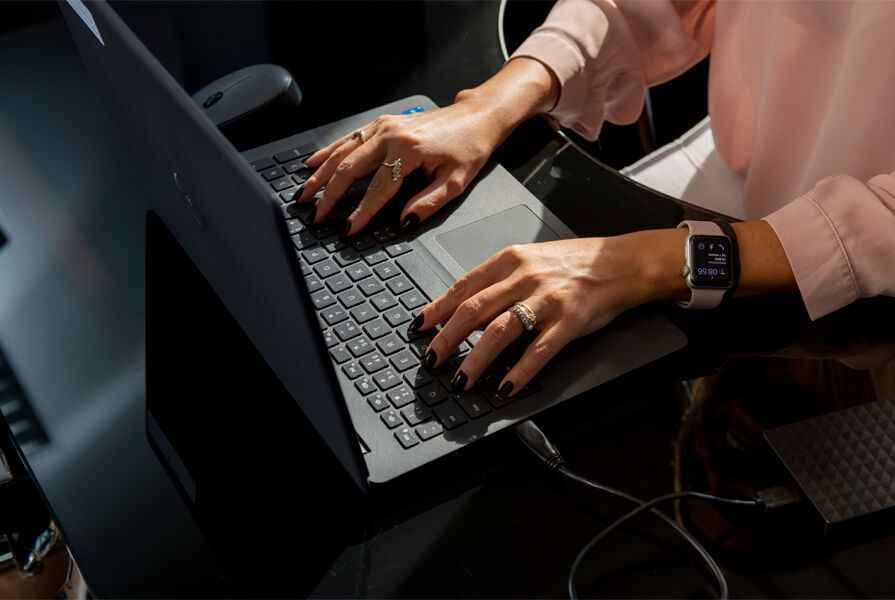 Mãos digitando em laptop moderno na mesa