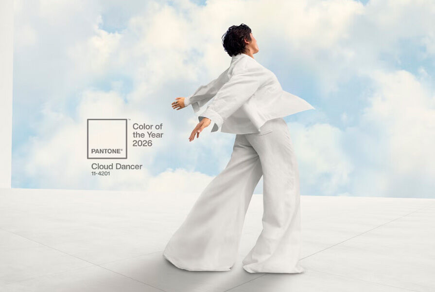 Modelo dançando com traje branco sob céu azul